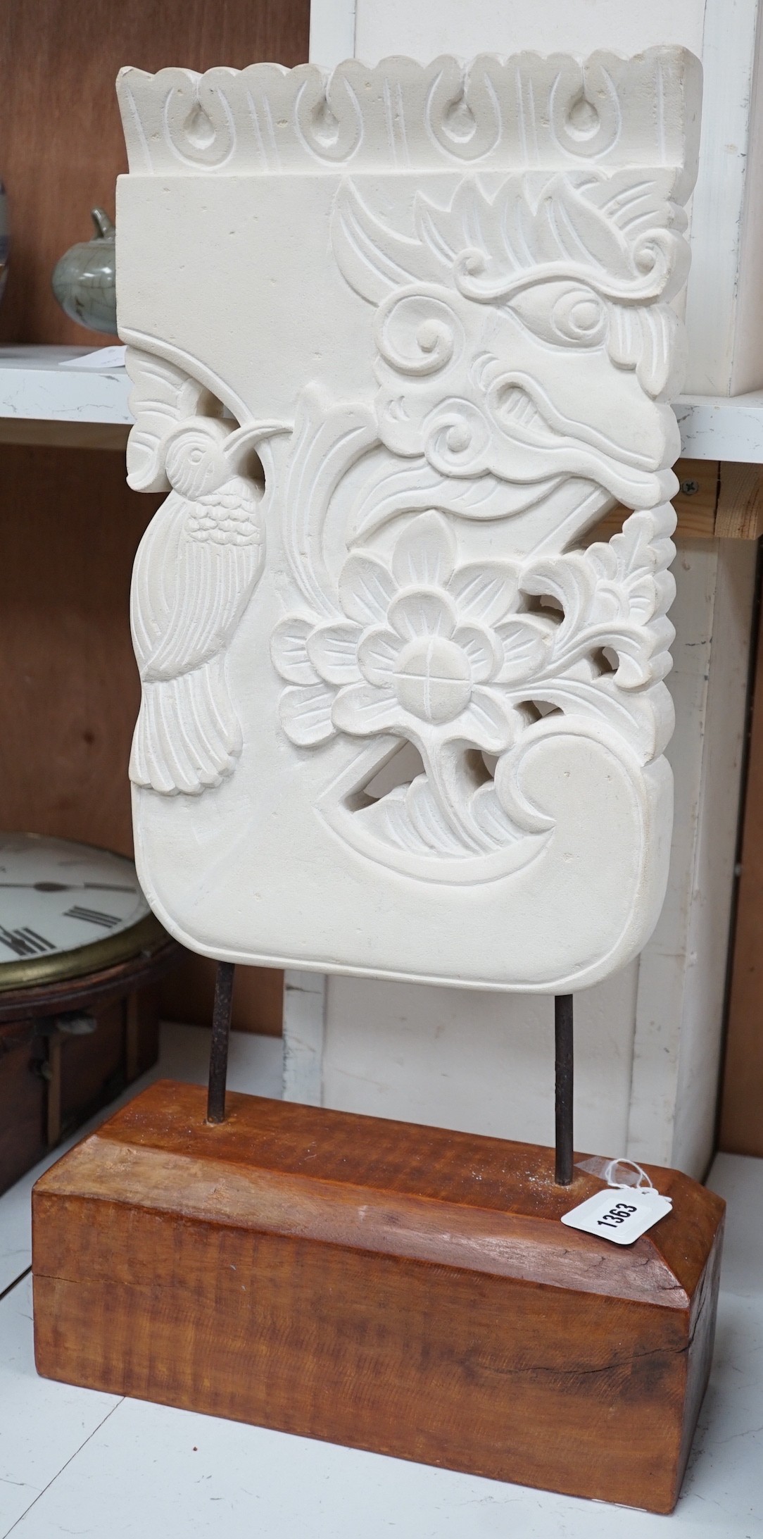 An Indonesian sandstone carving of a mask, bird and flowers on hardwood stand, 62.5cms high Height 63 cm.